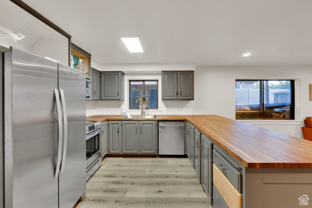 Kitchen featuring appliances with stainless steel finishes, wood counters, gray cabinetry, and recessed lighting