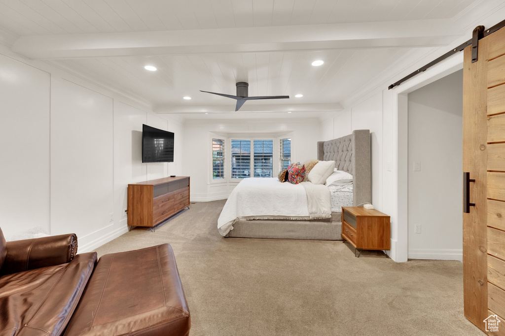 Bedroom with a barn door, beam ceiling, light colored carpet, recessed lighting, and baseboards