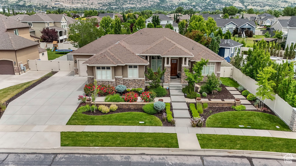 View of front of property with a gate, stone siding, driveway, stucco siding, and a residential view