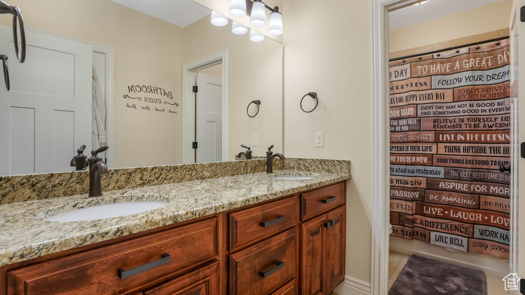 Full bath with double vanity, tile patterned flooring, and a shower with shower curtain
