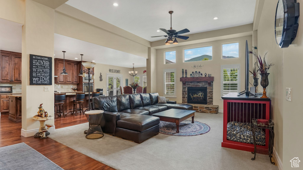 Living area with ceiling fan, recessed lighting, dark wood-style flooring, a stone fireplace, and a towering ceiling
