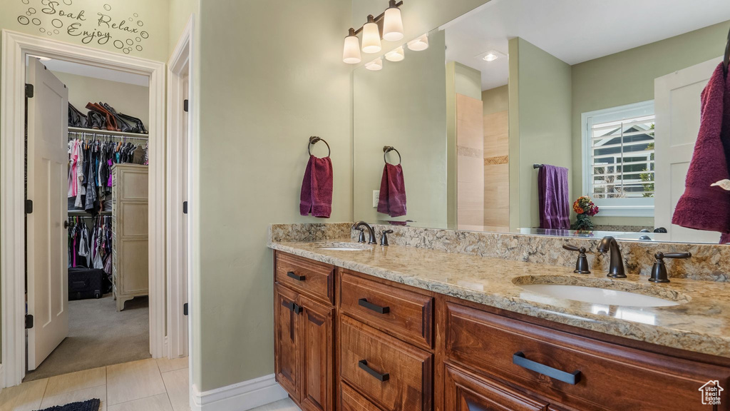 Full bath featuring double vanity, tile patterned flooring, and a walk in closet