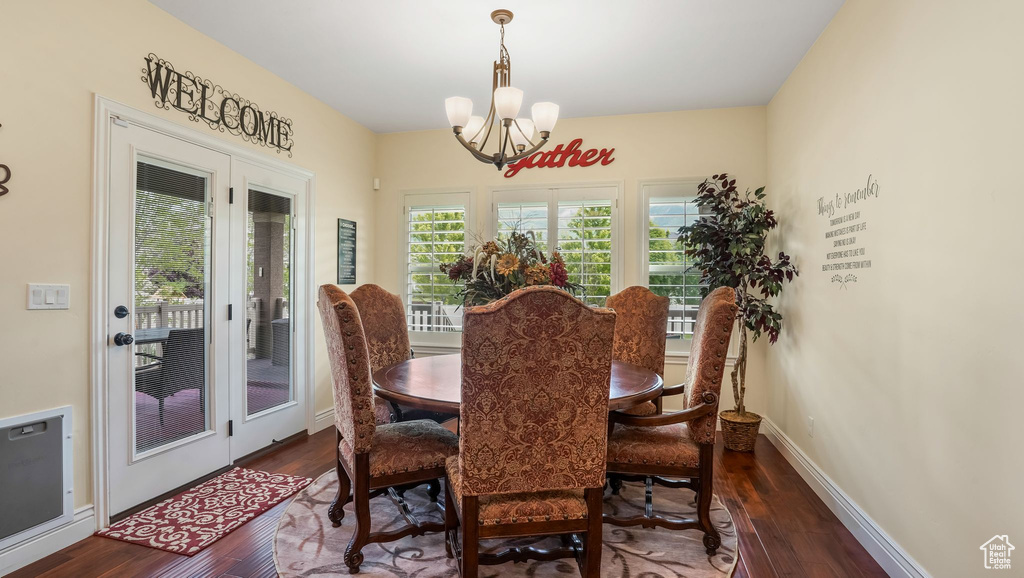 Dining room with dark wood finished floors, a chandelier, and baseboards