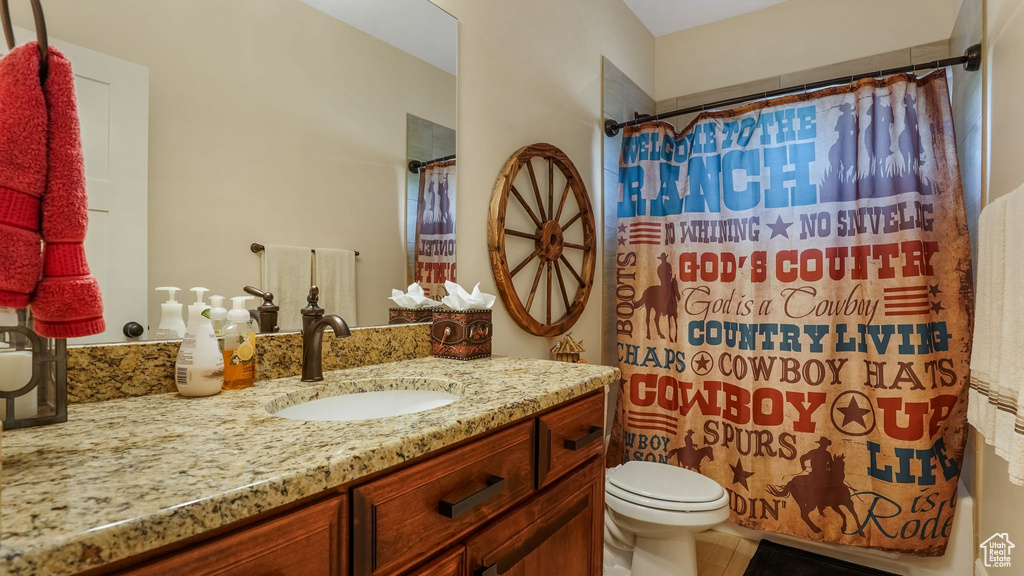 Bathroom with vanity, toilet, tile patterned floors, and shower / bath combo with shower curtain