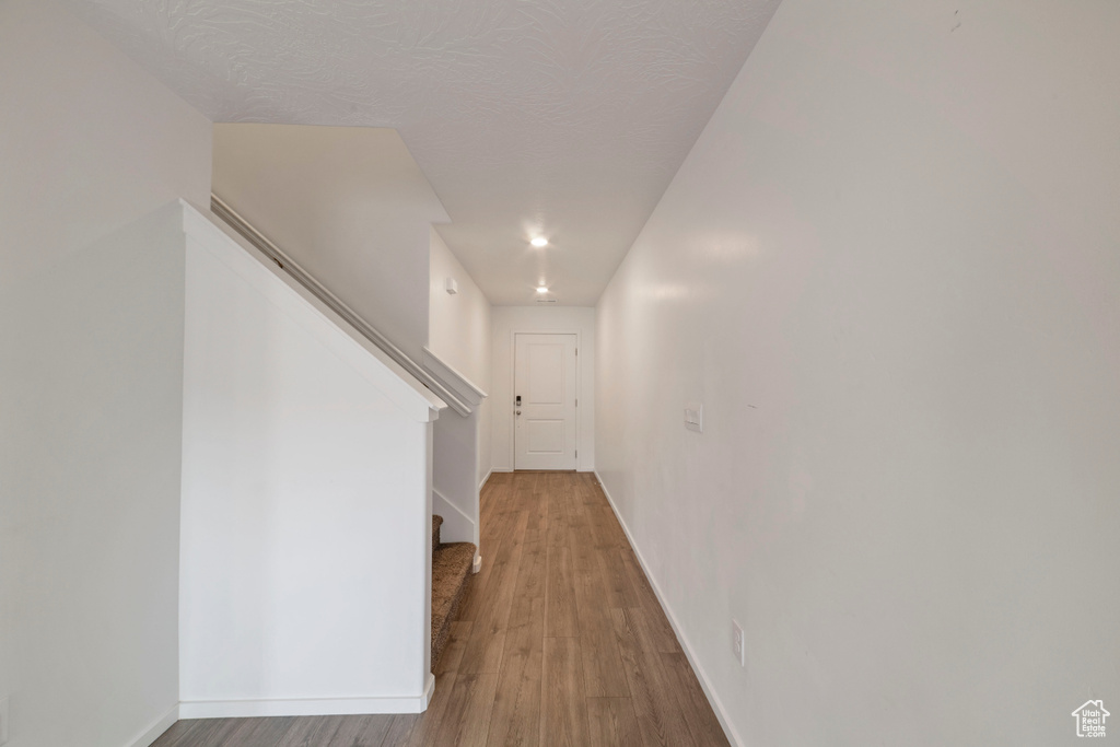 Hallway featuring stairs, wood finished floors, baseboards, and recessed lighting