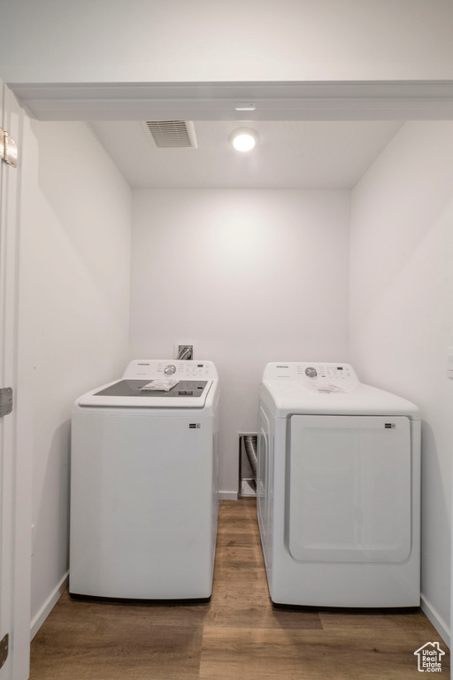 Laundry room featuring independent washer and dryer, wood finished floors, and baseboards