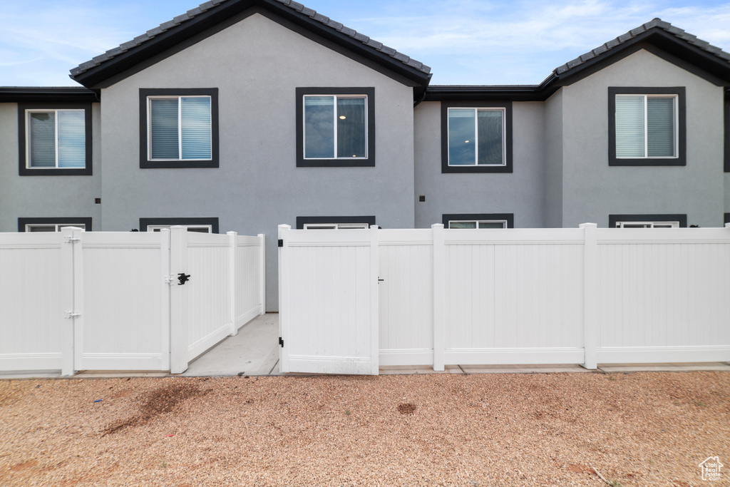 View of property exterior featuring a gate, stucco siding, and a tiled roof