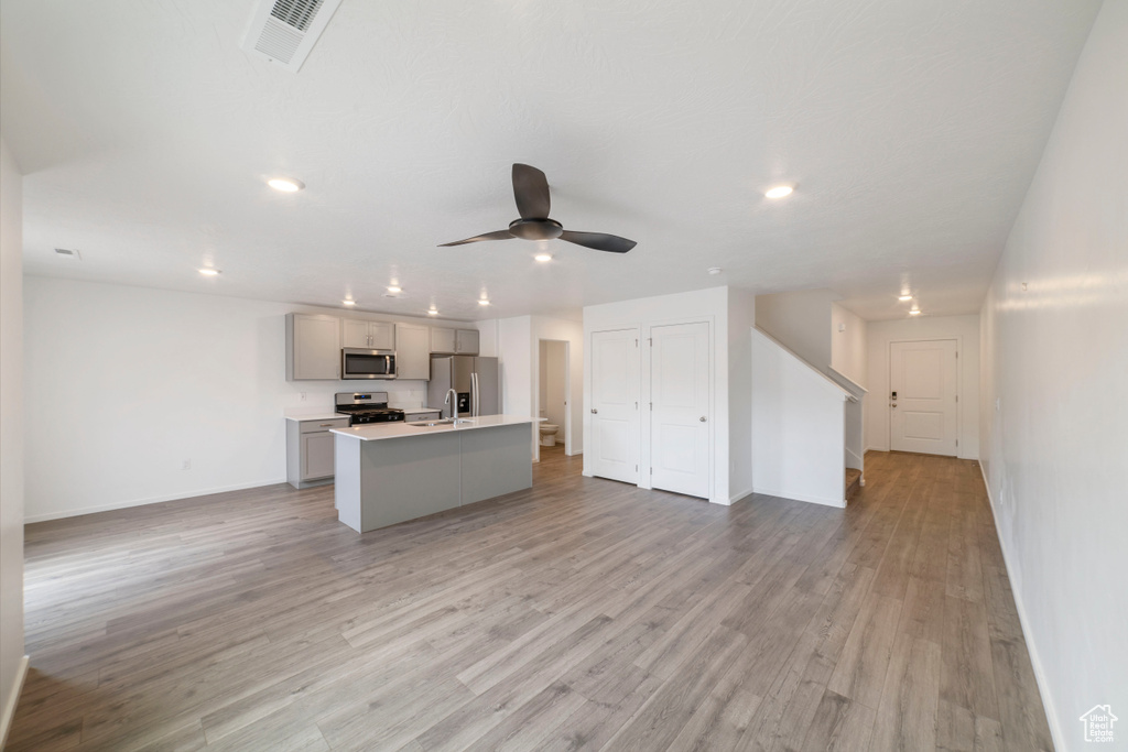 Kitchen with stainless steel appliances, open floor plan, baseboards, recessed lighting, and a kitchen island with sink