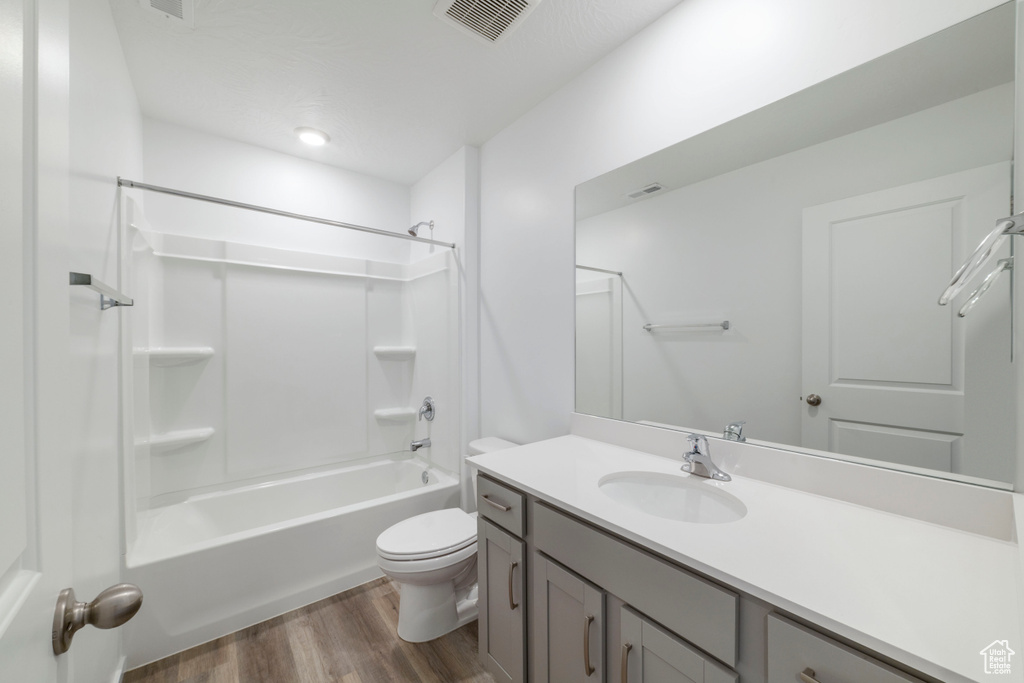 Full bath with wood finished floors, toilet, vanity, and shower / bath combination