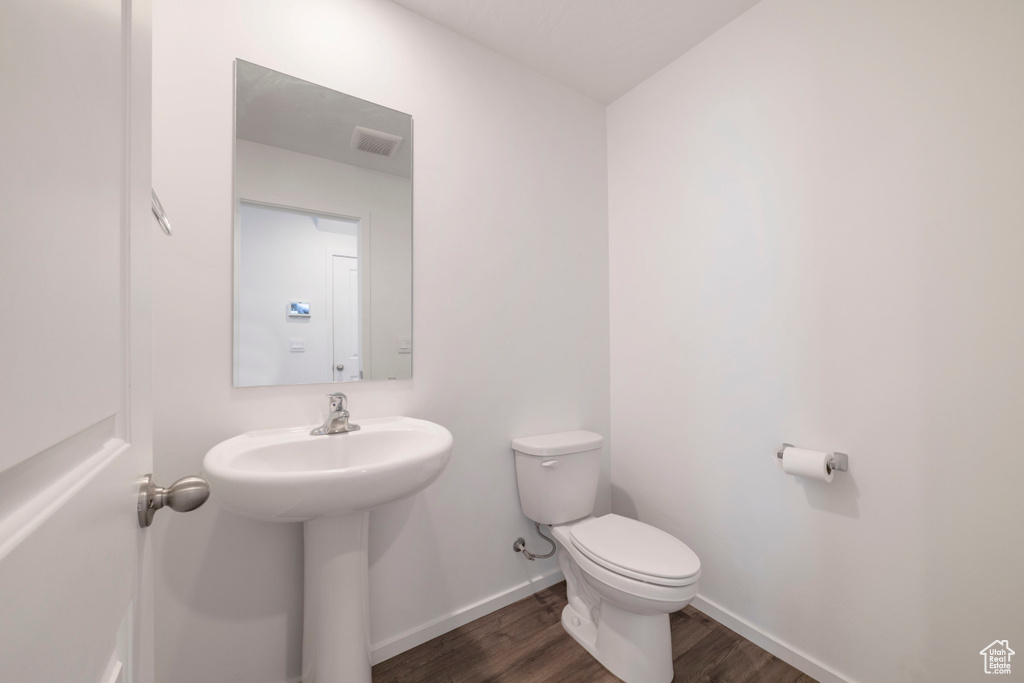 Bathroom featuring wood finished floors, toilet, and baseboards