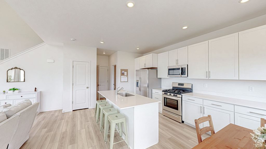 Kitchen with appliances with stainless steel finishes, a sink, light wood-style flooring, recessed lighting, and white cabinets