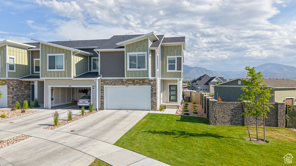 View of front of house with board and batten siding, driveway, an attached garage, and a mountain view