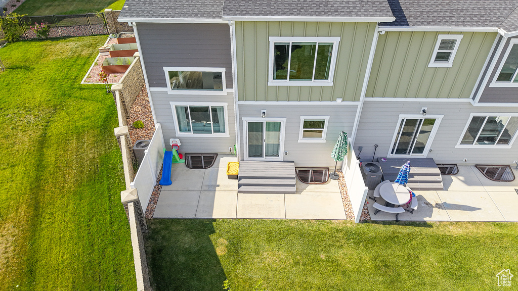 Rear view of house with a shingled roof, board and batten siding, and a patio