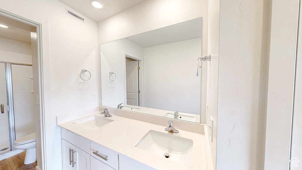 Full bath featuring toilet, double vanity, a shower stall, and recessed lighting