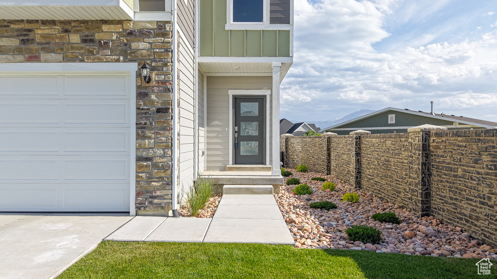 View of exterior entry with stone siding, board and batten siding, and a garage