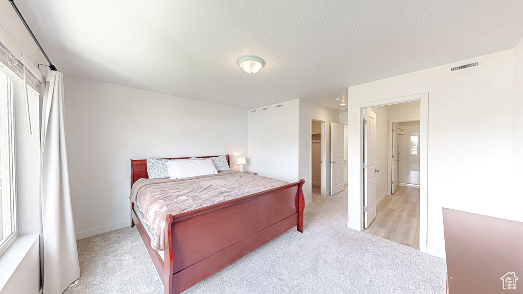 Bedroom with light colored carpet, baseboards, and a textured ceiling