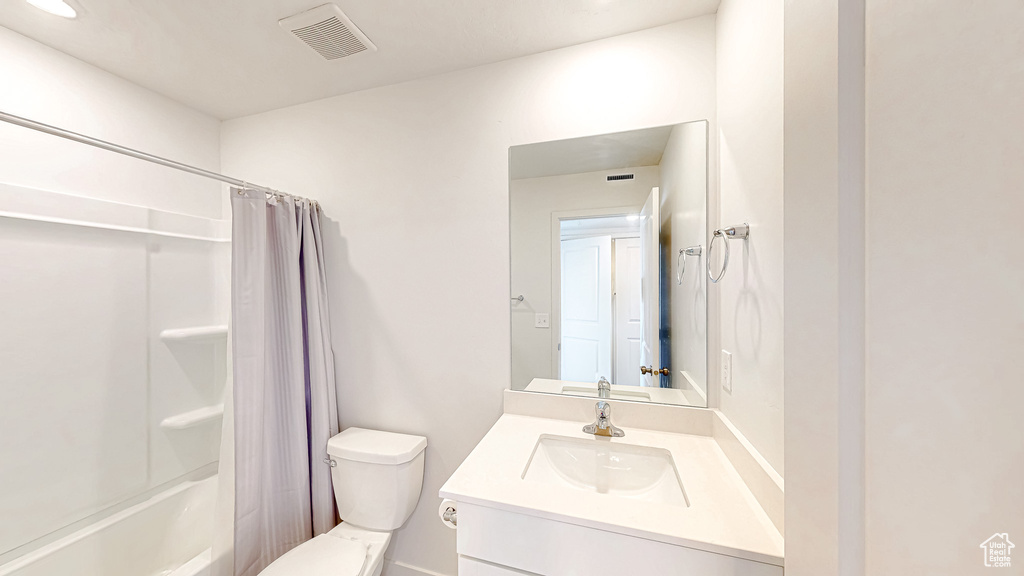 Bathroom with vanity, toilet, and shower / tub combo with curtain