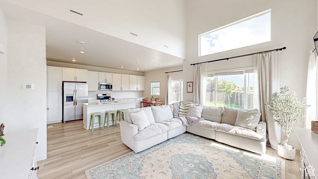 Living area with light wood-style flooring, a high ceiling, and recessed lighting
