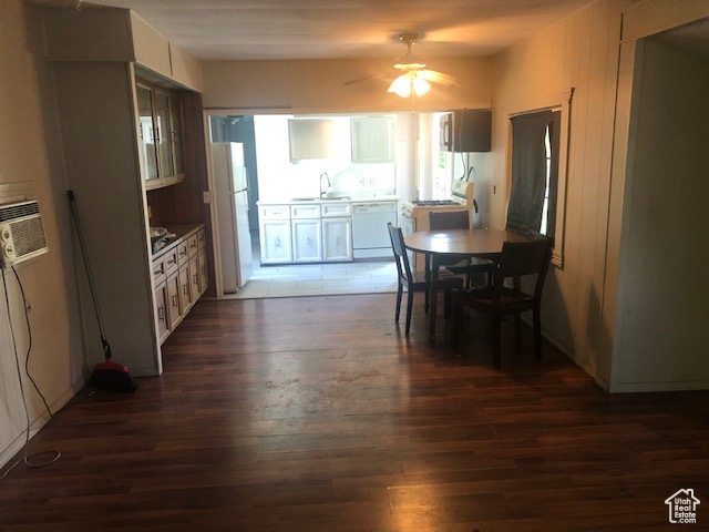 Dining area with dark wood-type flooring, a ceiling fan, and a wall mounted AC
