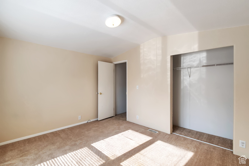 Unfurnished bedroom with carpet floors, lofted ceiling, and a closet