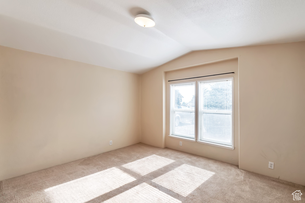 Empty room featuring carpet floors and lofted ceiling
