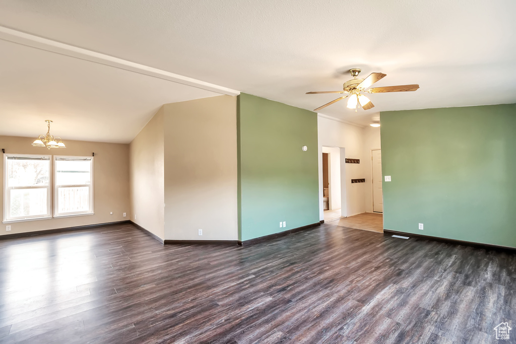Spare room featuring wood finished floors, a chandelier, a ceiling fan, and baseboards