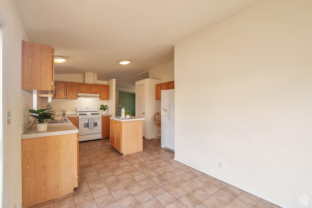 Kitchen with white appliances, light countertops, a center island, under cabinet range hood, and a sink