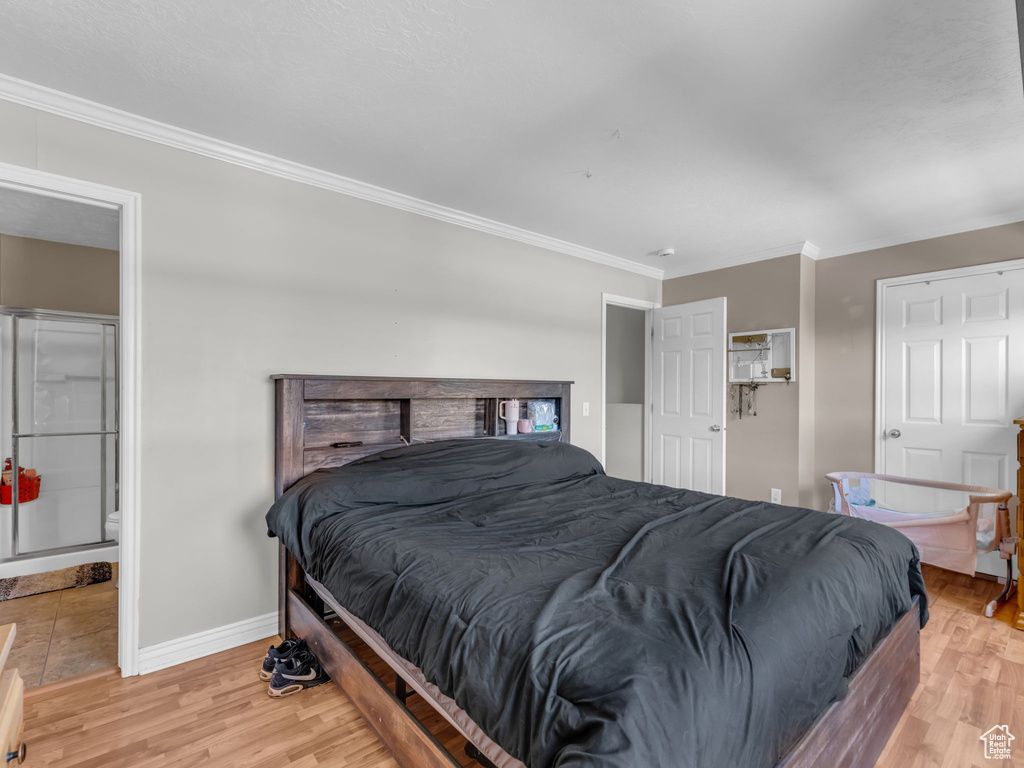 Bedroom with ornamental molding, light wood-style flooring, and baseboards