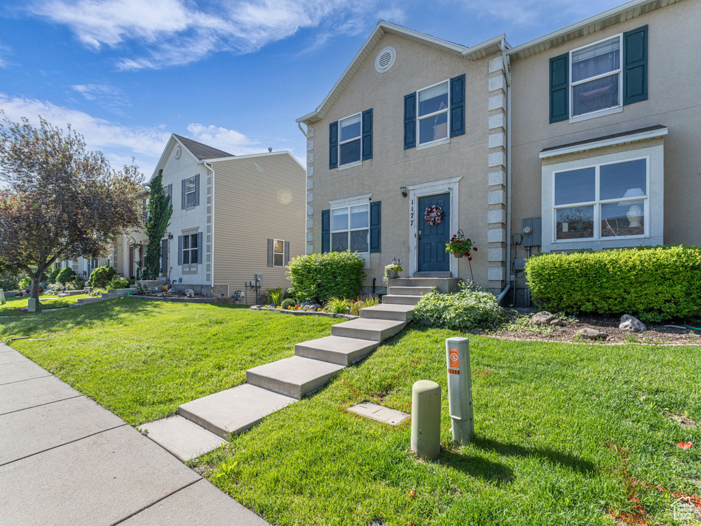 Townhome / multi-family property featuring a front yard and stucco siding