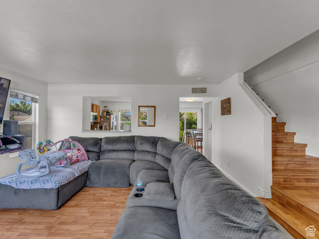 Living area with light wood-style floors, plenty of natural light, and stairway
