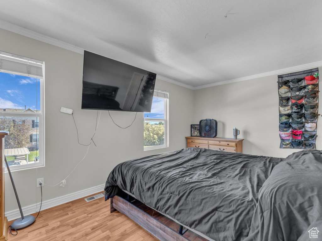 Bedroom with baseboards, light wood-style flooring, and crown molding