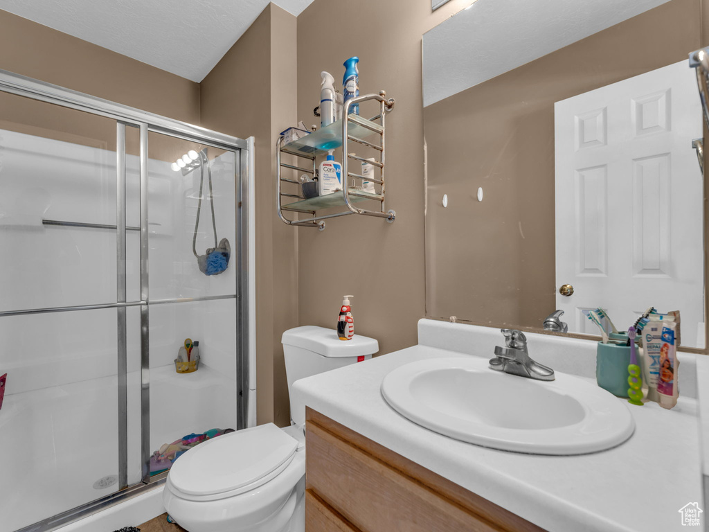 Full bath featuring vanity, toilet, and a shower stall