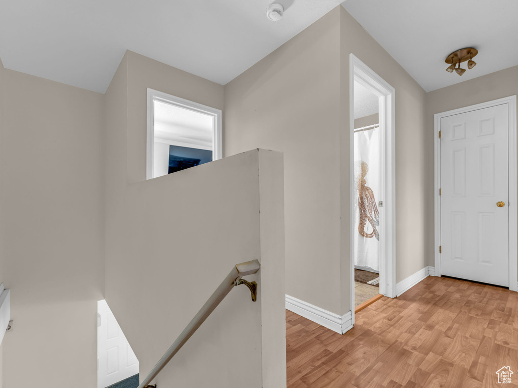 Corridor with an upstairs landing, light wood finished floors, and baseboards
