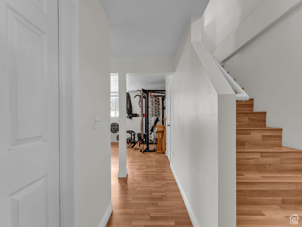Hallway with light wood finished floors, baseboards, and stairway