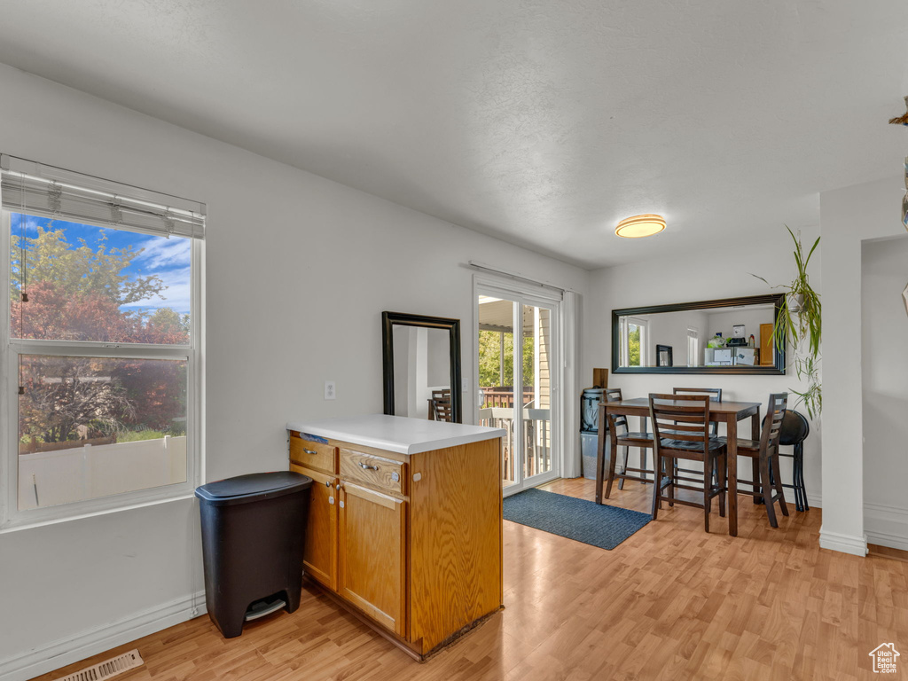 Kitchen featuring a peninsula, light wood-style flooring, brown cabinetry, light countertops, and baseboards