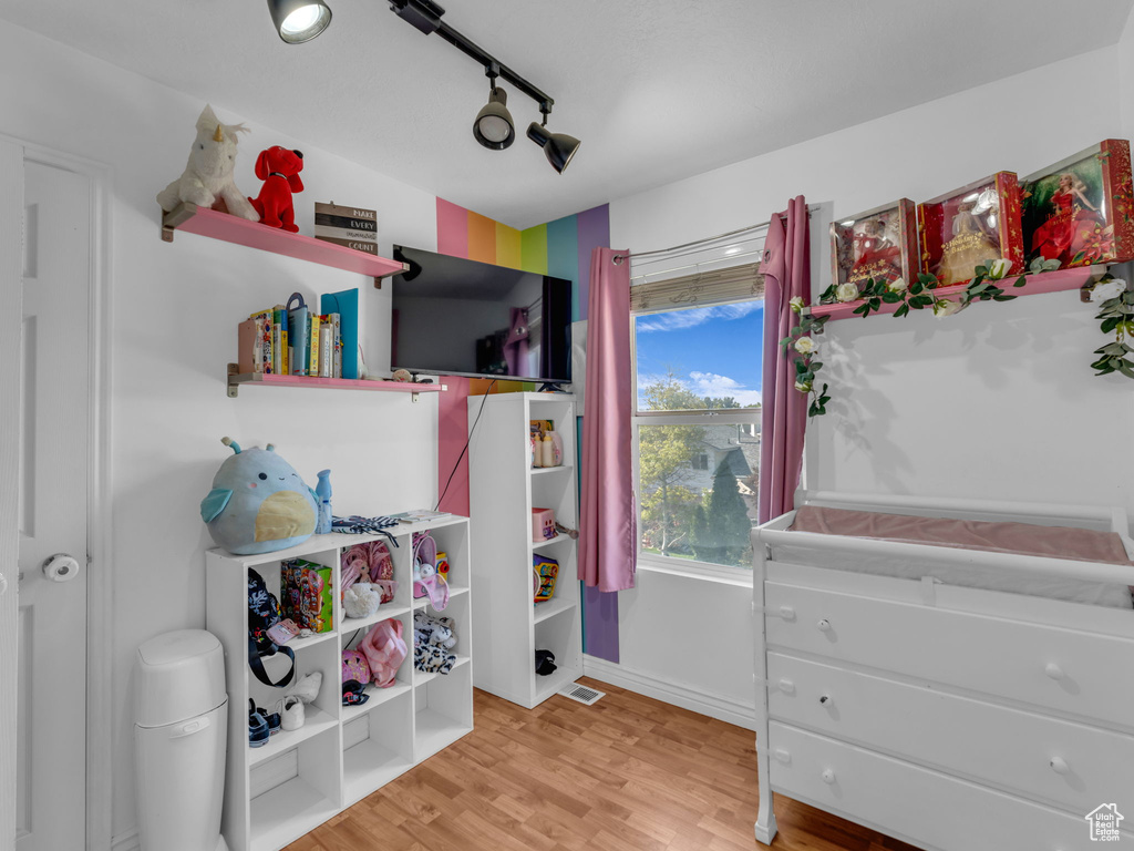 Bedroom with light wood finished floors, track lighting, and baseboards