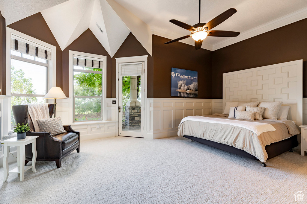 Bedroom with access to outside, carpet flooring, a decorative wall, wainscoting, and lofted ceiling