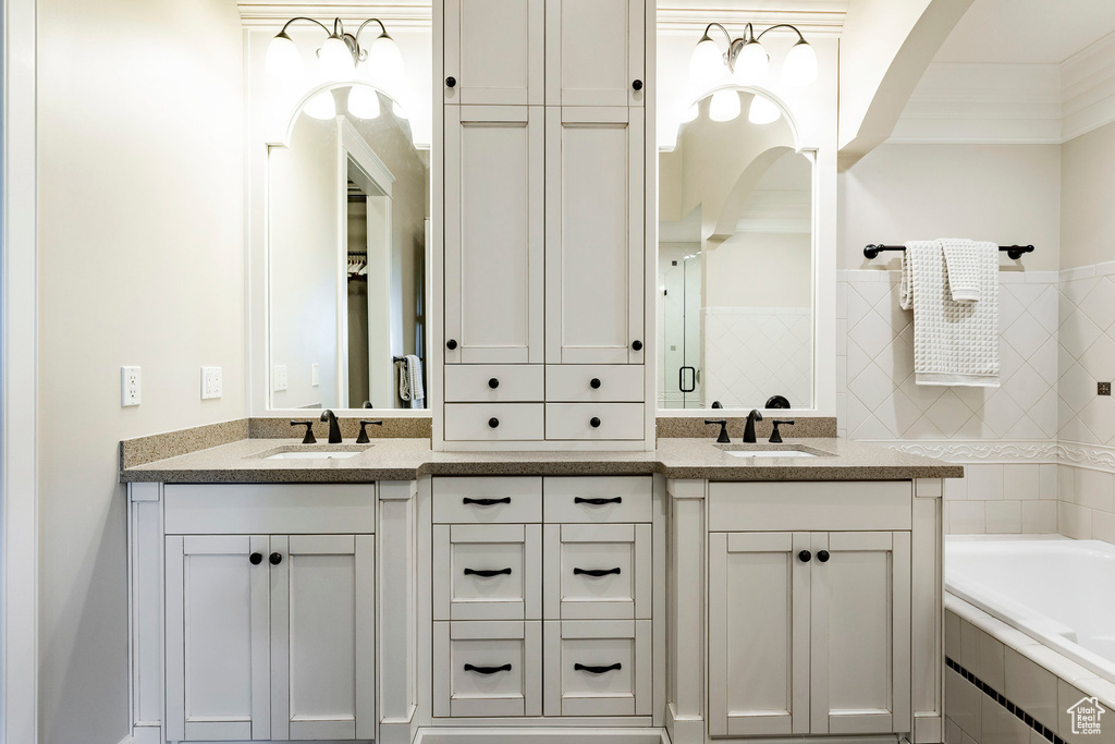 Bathroom featuring tiled bath, double vanity, and tiled shower
