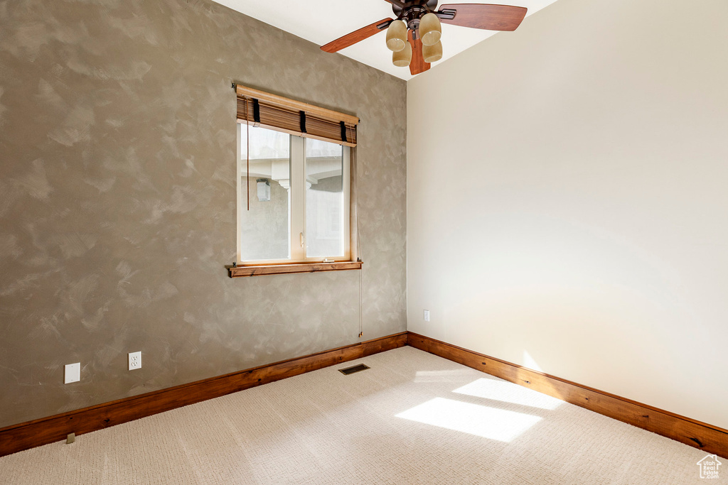 Carpeted spare room with baseboards and ceiling fan