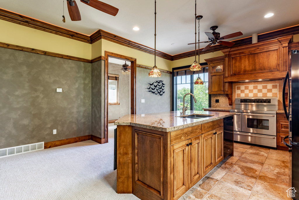 Kitchen featuring a ceiling fan, black appliances, a sink, crown molding, and a center island with sink