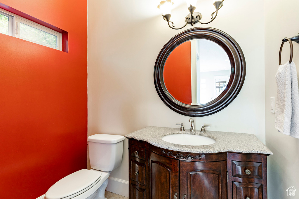 Half bath featuring toilet, vanity, and baseboards