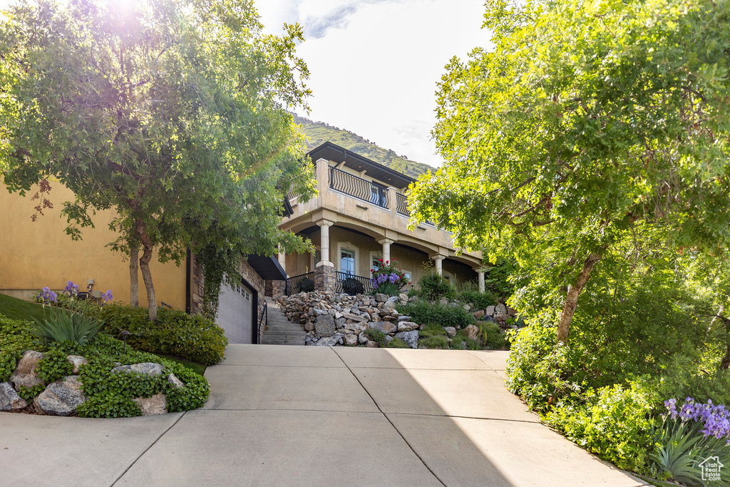 View of front of property with a balcony, concrete driveway, stucco siding, and a garage