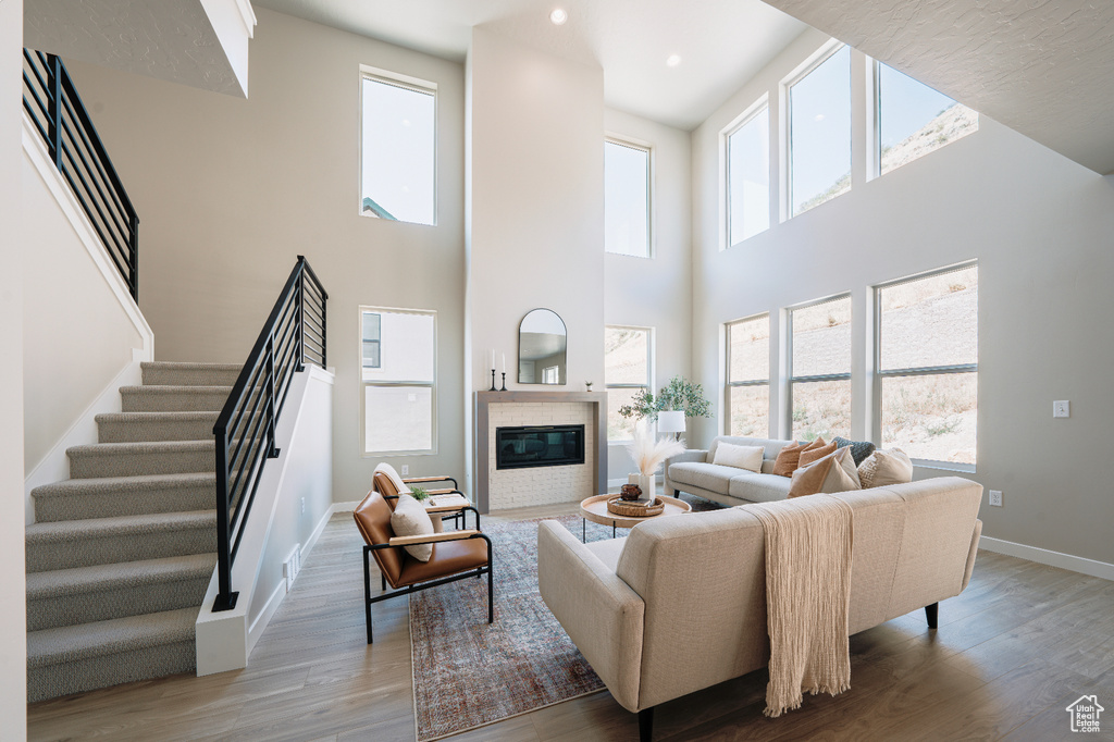 Living room featuring wood finished floors, baseboards, plenty of natural light, a towering ceiling, and recessed lighting