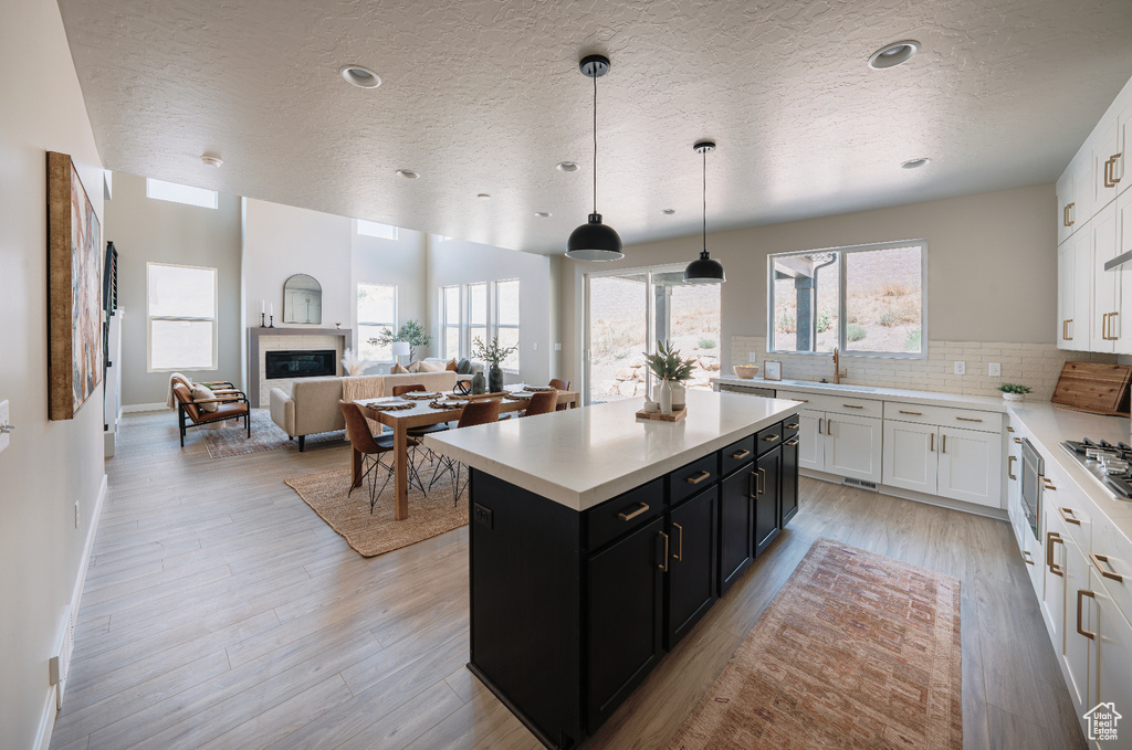 Kitchen with dark cabinets, a textured ceiling, white cabinetry, light countertops, and a center island