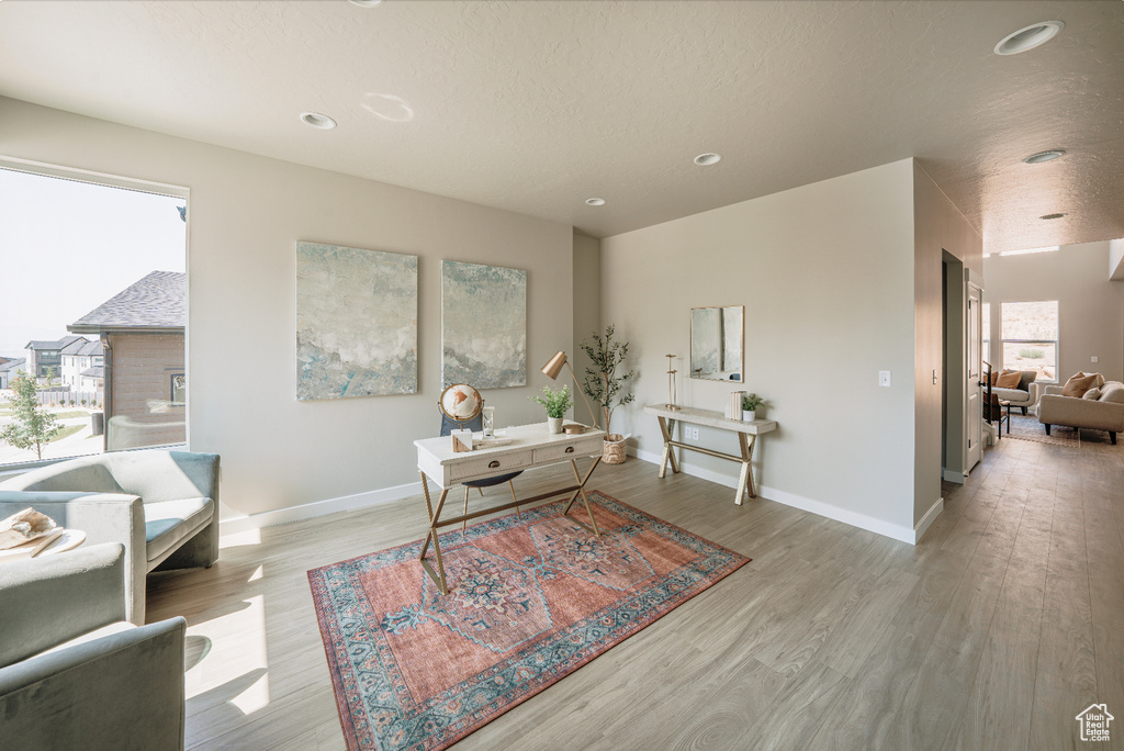 Home office with light wood-style floors, baseboards, recessed lighting, and a textured ceiling