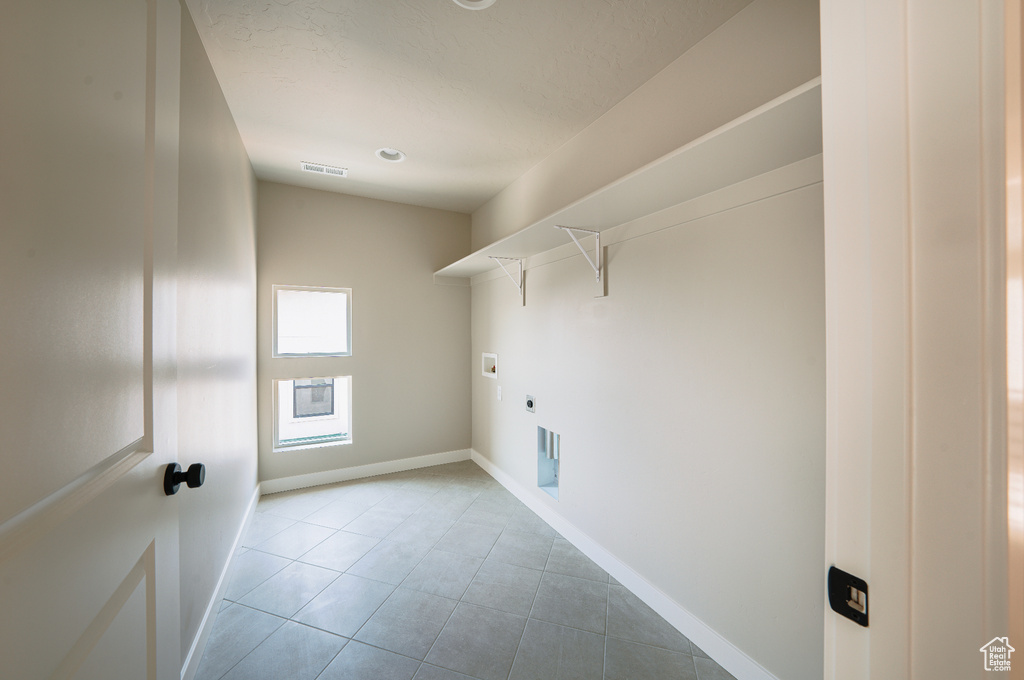 Washroom with tile patterned floors, hookup for a washing machine, hookup for an electric dryer, and baseboards