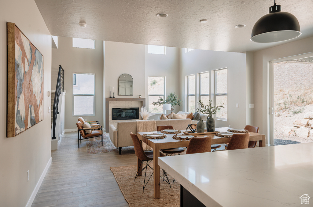 Dining area with a textured ceiling, wood finished floors, baseboards, and a glass covered fireplace