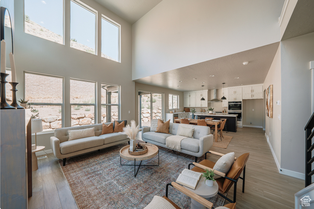 Living area featuring a high ceiling, light wood finished floors, and baseboards