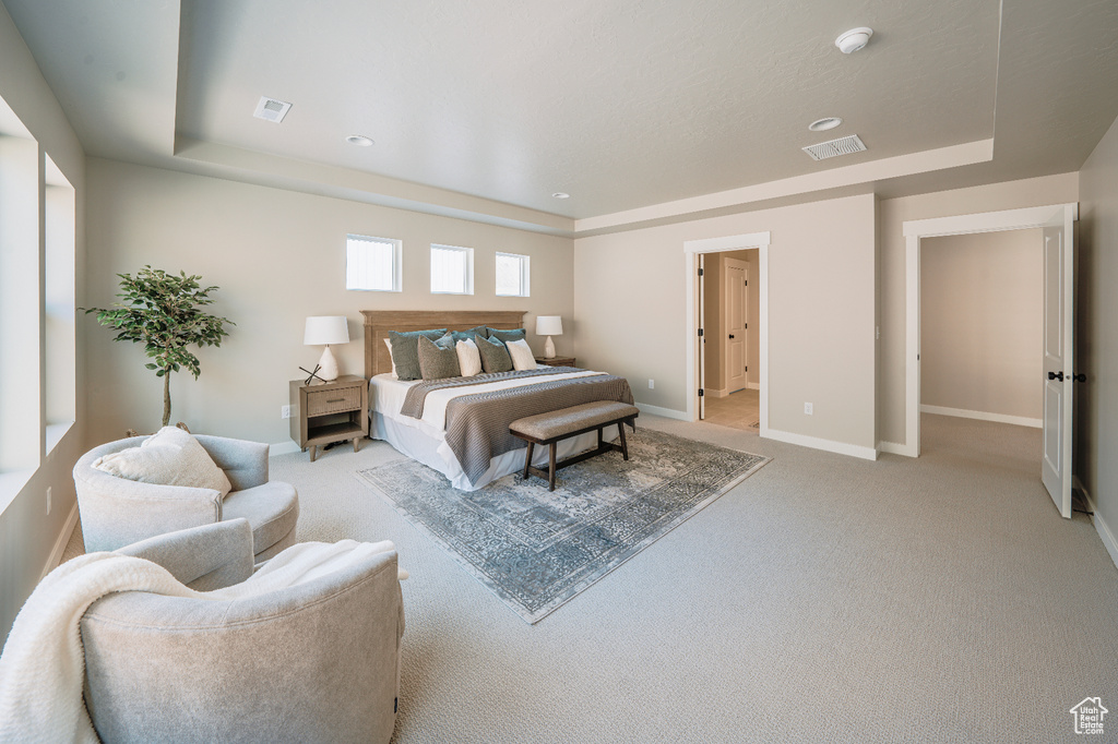 Bedroom featuring a raised ceiling, light colored carpet, baseboards, and recessed lighting