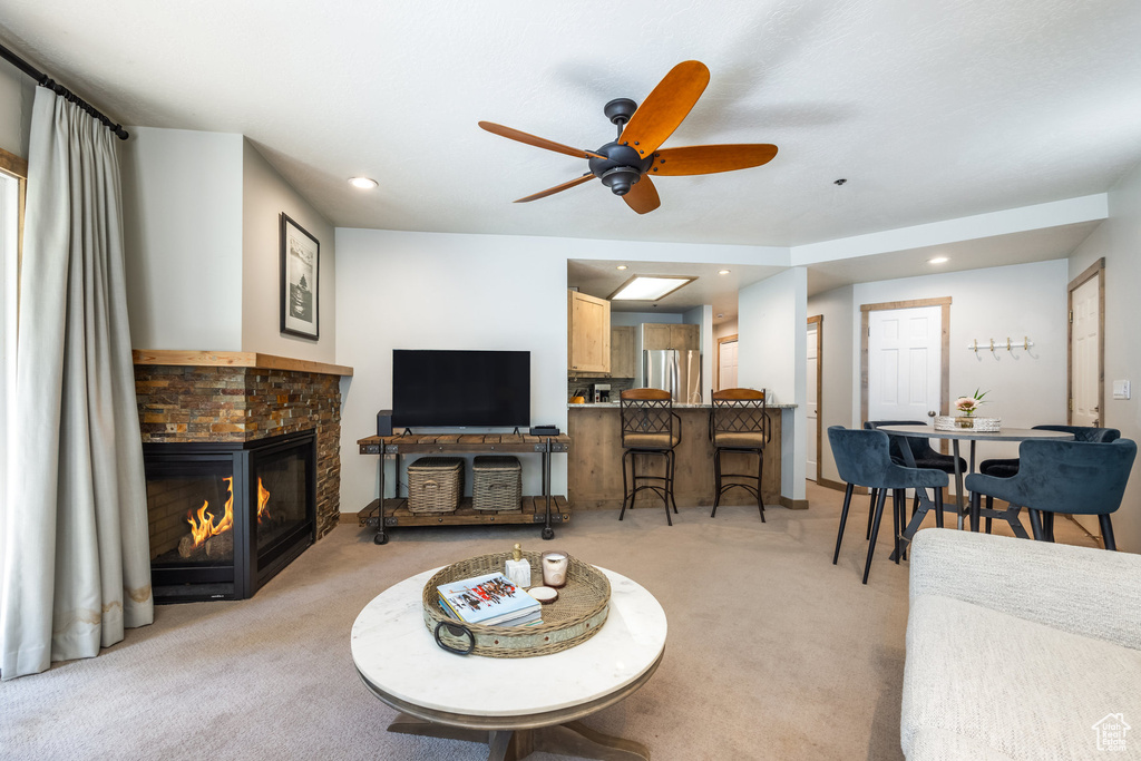 Living area featuring light colored carpet, ceiling fan, recessed lighting, a glass covered fireplace, and baseboards